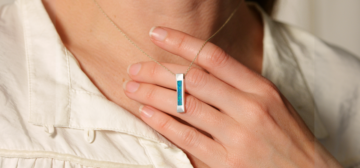 Opals & Ashes Bar Unisex Memorial Pendant Silver. Modelled on female. Ashes blended with Pacific Blue Opals.